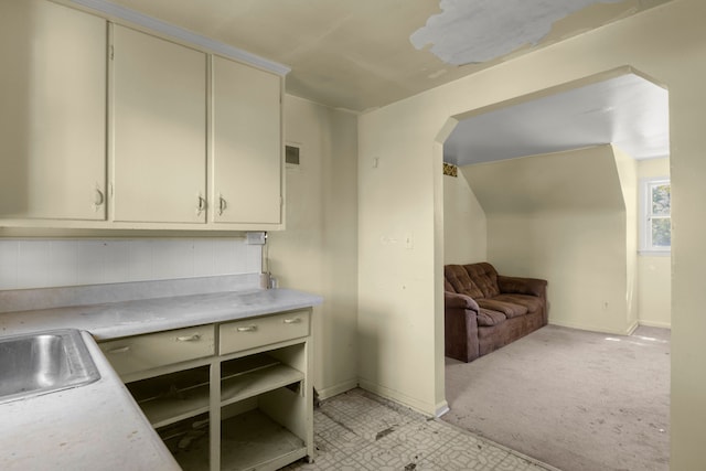 kitchen with cream cabinets, light colored carpet, and sink