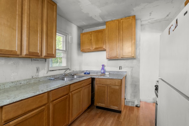 kitchen featuring white fridge, light stone countertops, sink, and light hardwood / wood-style flooring