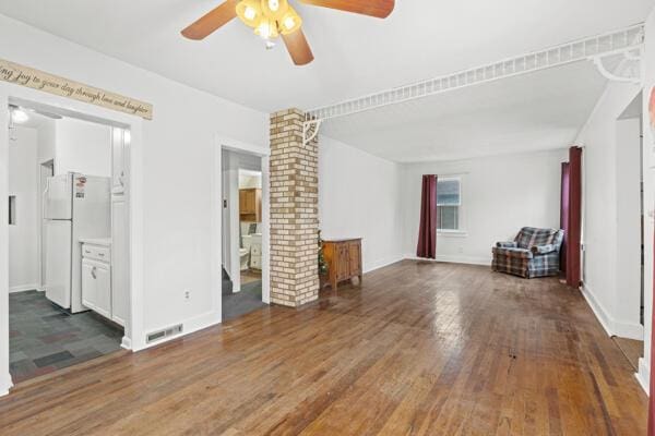 unfurnished living room with dark hardwood / wood-style floors, ceiling fan, and ornate columns