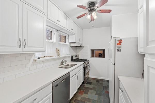 kitchen with white cabinetry, sink, ceiling fan, stainless steel appliances, and backsplash