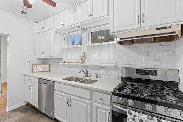 kitchen with sink, dark wood-type flooring, tasteful backsplash, white cabinets, and appliances with stainless steel finishes