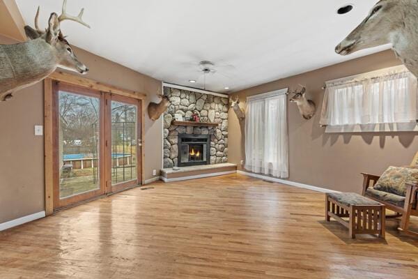 unfurnished living room with a stone fireplace and light wood-type flooring