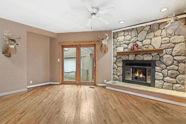 unfurnished living room featuring a fireplace, light wood-type flooring, and ceiling fan