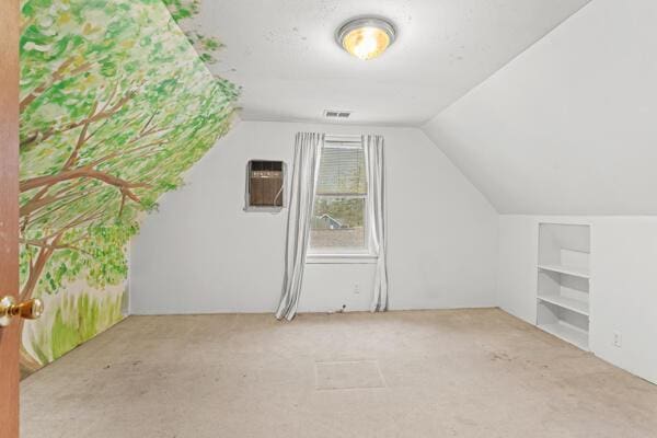 additional living space featuring a wall unit AC, built in features, light colored carpet, and lofted ceiling