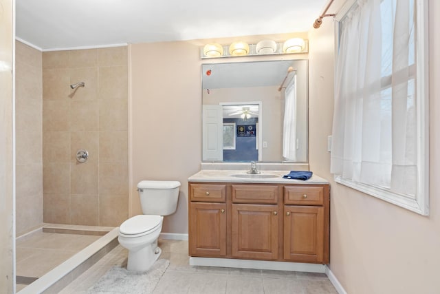 bathroom featuring vanity, tile patterned flooring, ceiling fan, toilet, and a tile shower