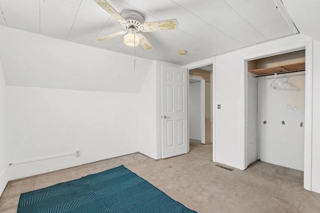 unfurnished bedroom featuring a closet, light colored carpet, ceiling fan, and lofted ceiling