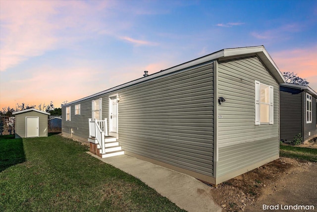 property exterior at dusk with a lawn and a shed