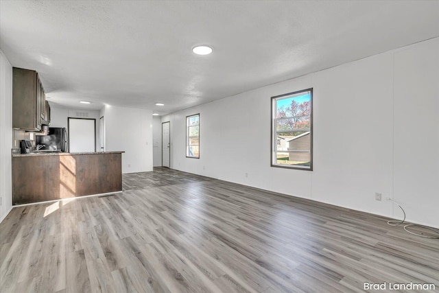 unfurnished living room with a textured ceiling and light hardwood / wood-style flooring