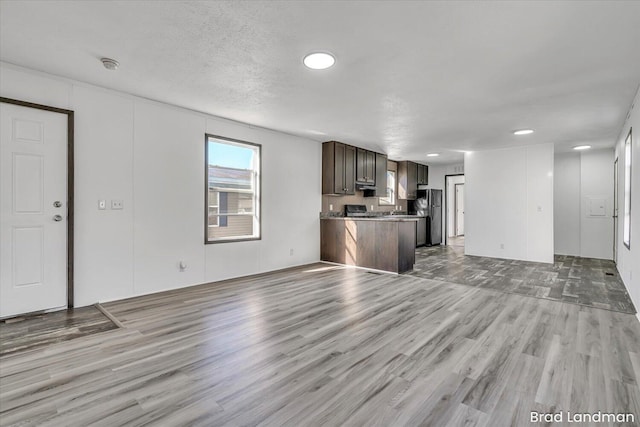 unfurnished living room with a textured ceiling and light hardwood / wood-style flooring