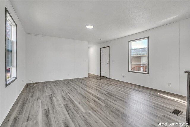 spare room with light wood-type flooring and a textured ceiling