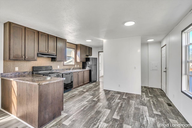 kitchen with dark hardwood / wood-style floors, plenty of natural light, and black appliances