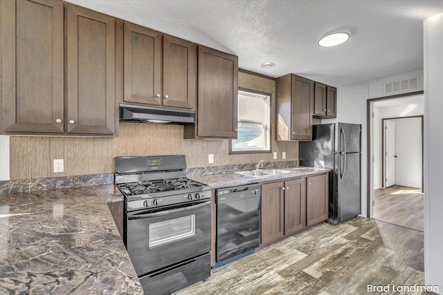 kitchen featuring dark brown cabinetry, sink, light hardwood / wood-style floors, a textured ceiling, and black appliances