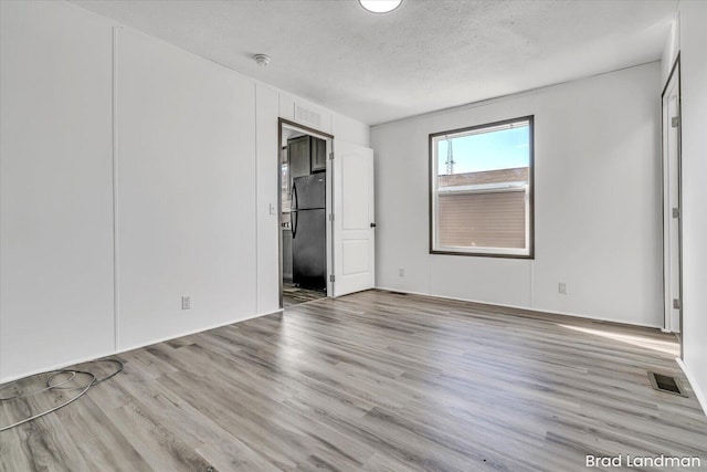 unfurnished room with light hardwood / wood-style floors and a textured ceiling