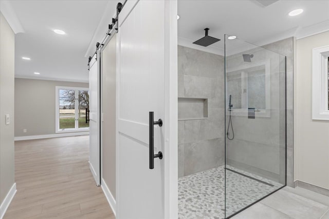 bathroom with tiled shower, crown molding, and hardwood / wood-style flooring