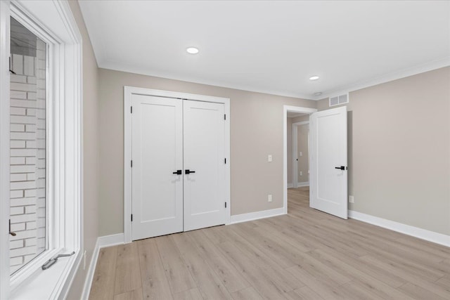 unfurnished bedroom featuring light hardwood / wood-style floors, ornamental molding, and a closet