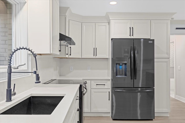 kitchen featuring sink, white cabinetry, fridge with ice dispenser, and light hardwood / wood-style flooring