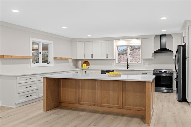 kitchen with a center island, wall chimney exhaust hood, stainless steel electric range oven, fridge, and white cabinetry