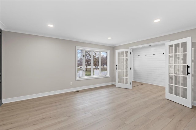 empty room with light wood-type flooring, crown molding, and french doors