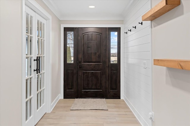 entrance foyer featuring french doors, ornamental molding, and light wood-type flooring