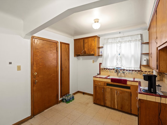 kitchen featuring decorative backsplash, tile countertops, and sink