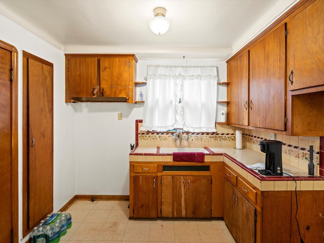 kitchen with tile counters, light tile patterned flooring, sink, and tasteful backsplash