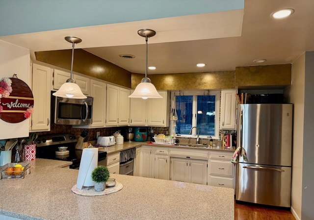 kitchen featuring white cabinetry, sink, stainless steel appliances, and decorative light fixtures