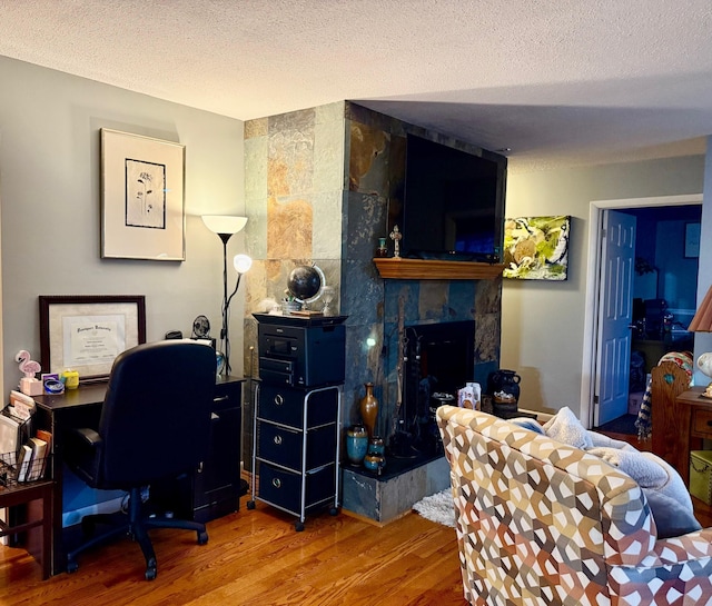 office area with hardwood / wood-style floors, a premium fireplace, and a textured ceiling