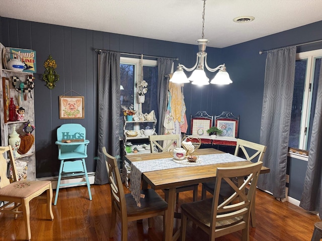 dining space with a textured ceiling, dark hardwood / wood-style floors, an inviting chandelier, and a baseboard heating unit