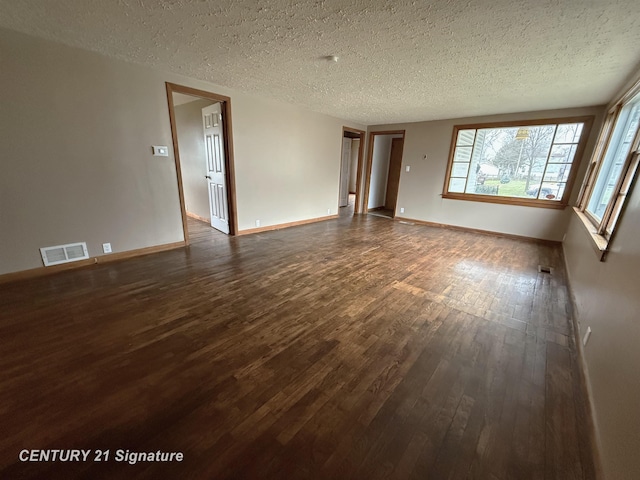 unfurnished living room with dark hardwood / wood-style flooring and a textured ceiling