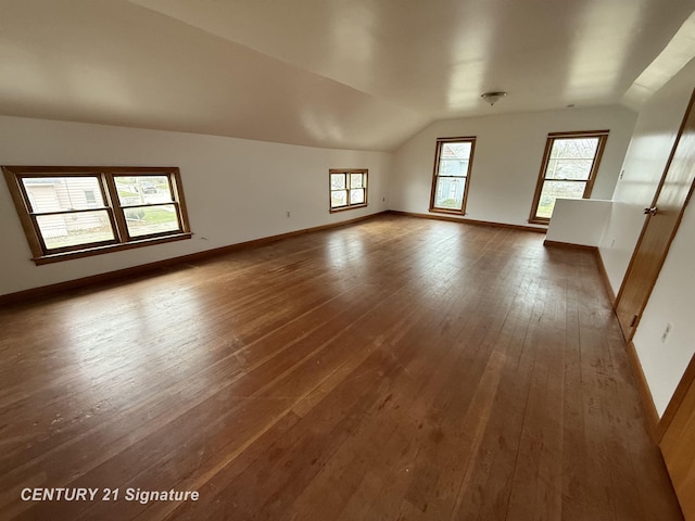 unfurnished room with wood-type flooring, vaulted ceiling, and a healthy amount of sunlight