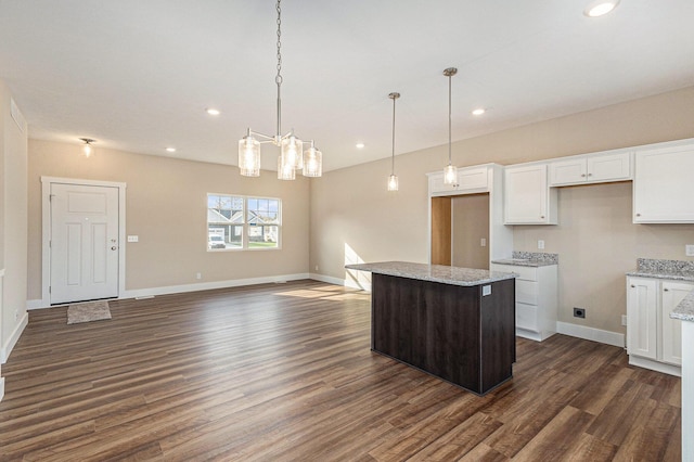 kitchen featuring a center island, white cabinets, hanging light fixtures, dark hardwood / wood-style flooring, and light stone counters