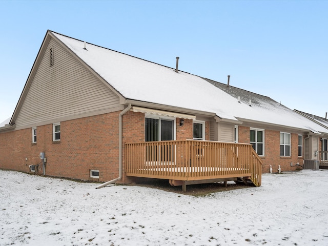 snow covered rear of property featuring a deck