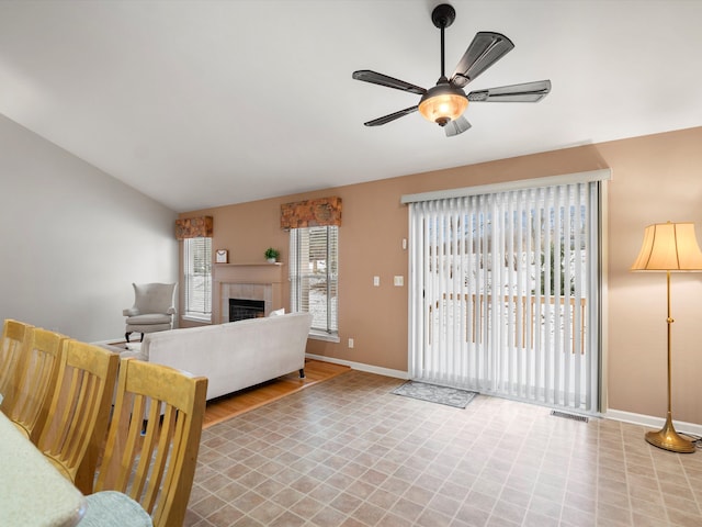 living room with ceiling fan, a fireplace, and vaulted ceiling