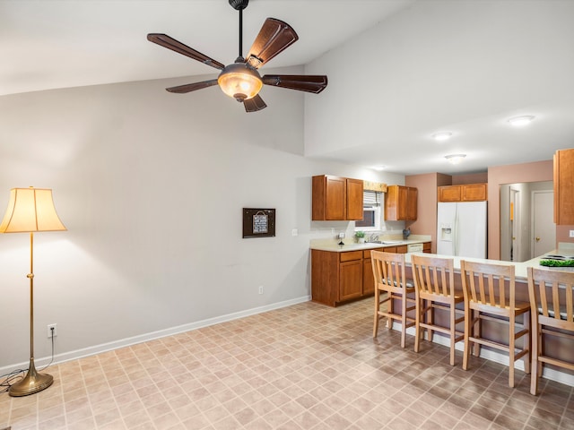 kitchen featuring ceiling fan, white fridge with ice dispenser, and high vaulted ceiling