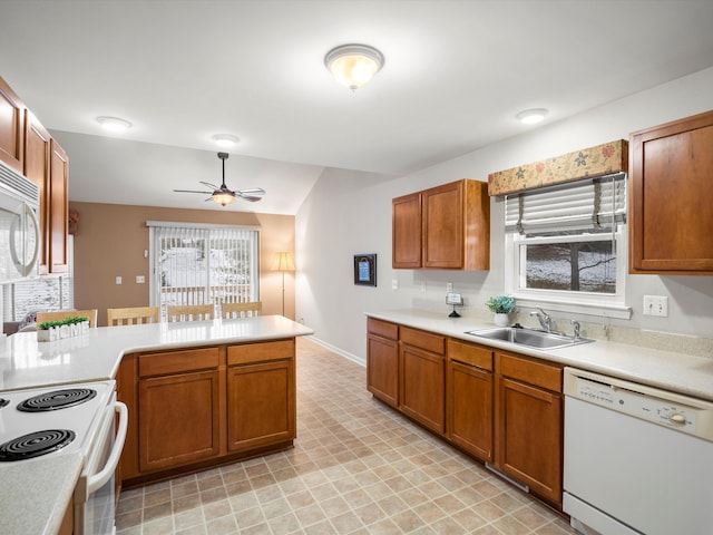 kitchen with kitchen peninsula, ceiling fan, sink, and white appliances