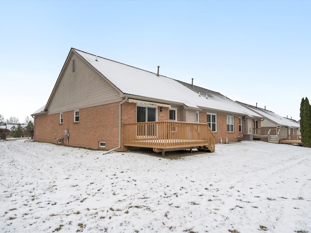 snow covered rear of property with a wooden deck