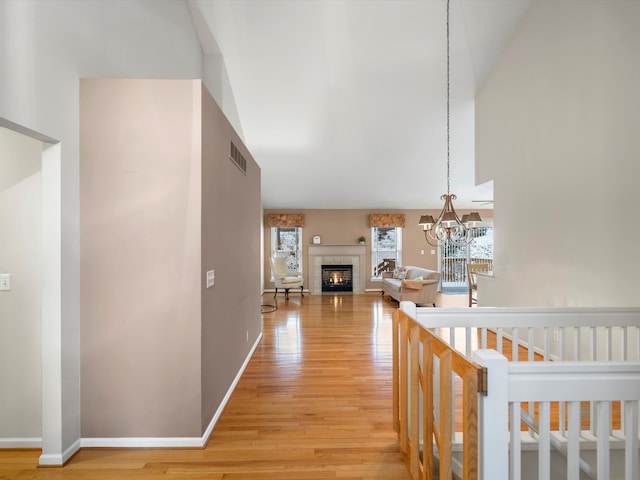 corridor with light hardwood / wood-style floors and an inviting chandelier