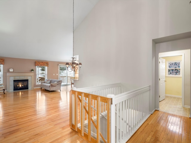 corridor featuring wood-type flooring, high vaulted ceiling, and an inviting chandelier