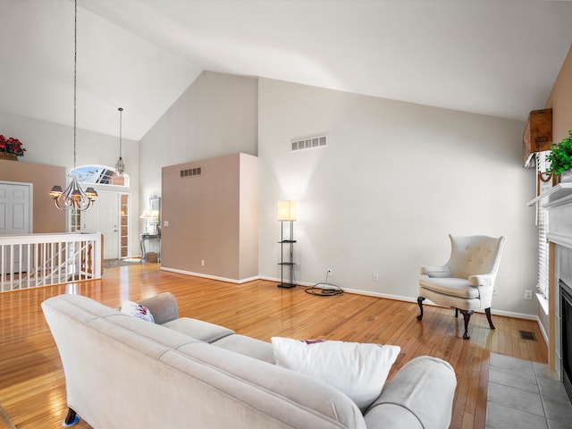 living room with a tile fireplace, a chandelier, high vaulted ceiling, and hardwood / wood-style flooring