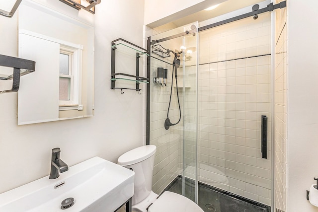 bathroom featuring a shower with door, vanity, and toilet