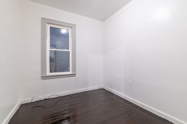 empty room featuring ornamental molding and dark wood-type flooring