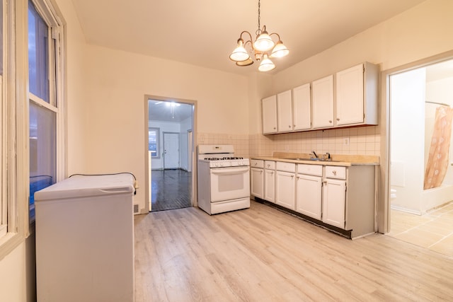 kitchen featuring an inviting chandelier, white cabinets, sink, hanging light fixtures, and gas range gas stove