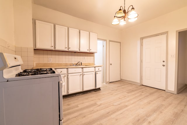 kitchen featuring white cabinets, white gas range oven, a notable chandelier, and sink