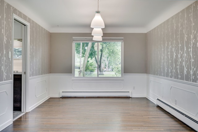 unfurnished dining area with wood-type flooring and a baseboard heating unit