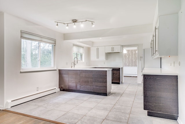 kitchen with baseboard heating, kitchen peninsula, white cabinetry, and light tile patterned floors