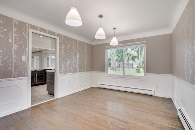 unfurnished dining area featuring hardwood / wood-style floors and a baseboard heating unit