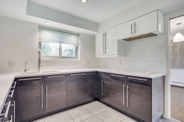 kitchen featuring white cabinets, sink, hanging light fixtures, light tile patterned floors, and baseboard heating