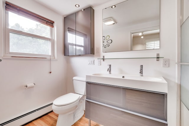 bathroom featuring vanity, toilet, wood-type flooring, and a baseboard radiator