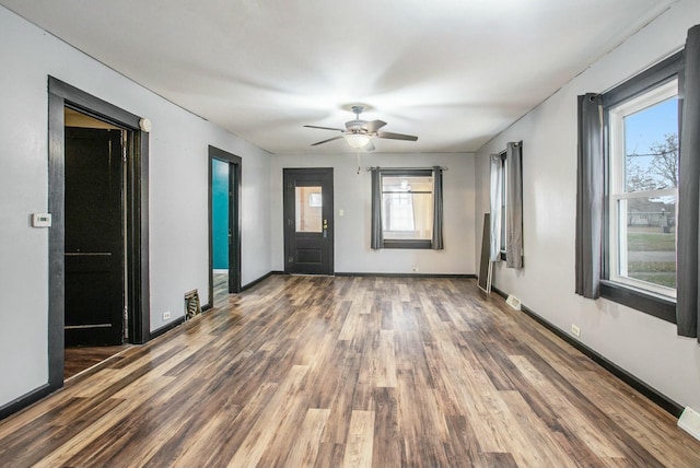 spare room with a wealth of natural light, ceiling fan, and dark wood-type flooring