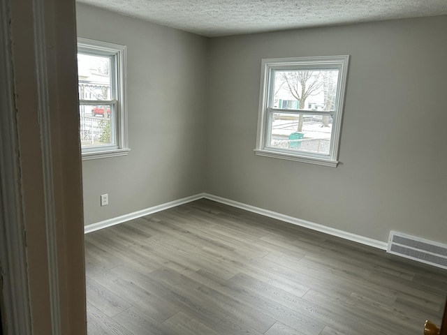 empty room with wood-type flooring and a textured ceiling